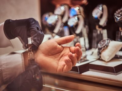 Assistant helps the client to try on exclusive men's watches, close-up hands.